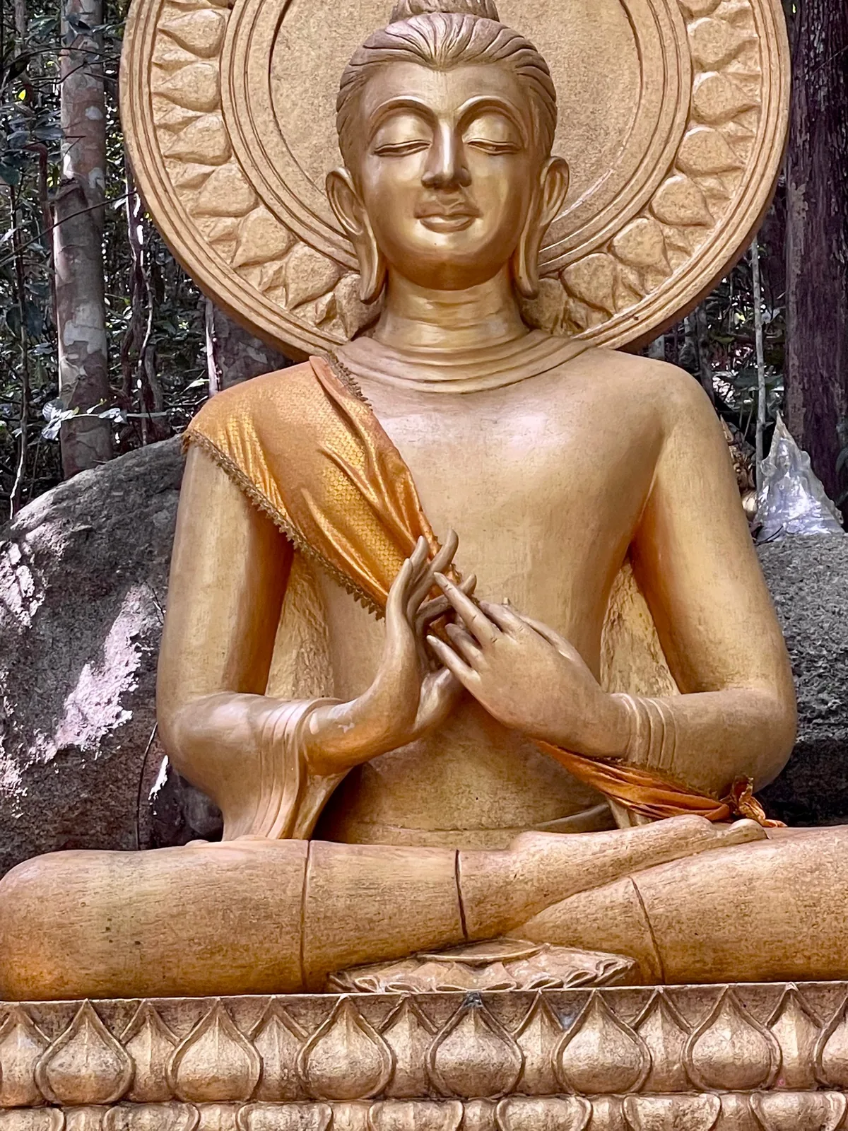 A golden Buddha sitting in lotus position on a boulder in Thailand