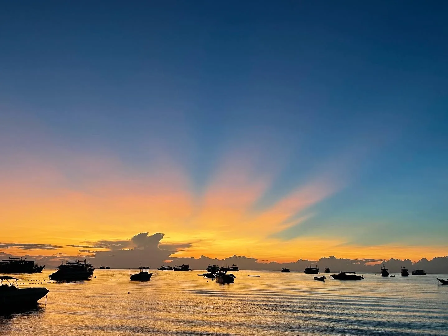 Blue yellow and orange sunset over the ocean with boats