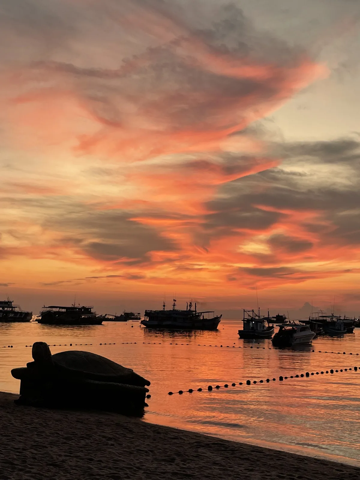 An orange sunset with a turtle statue on the beach