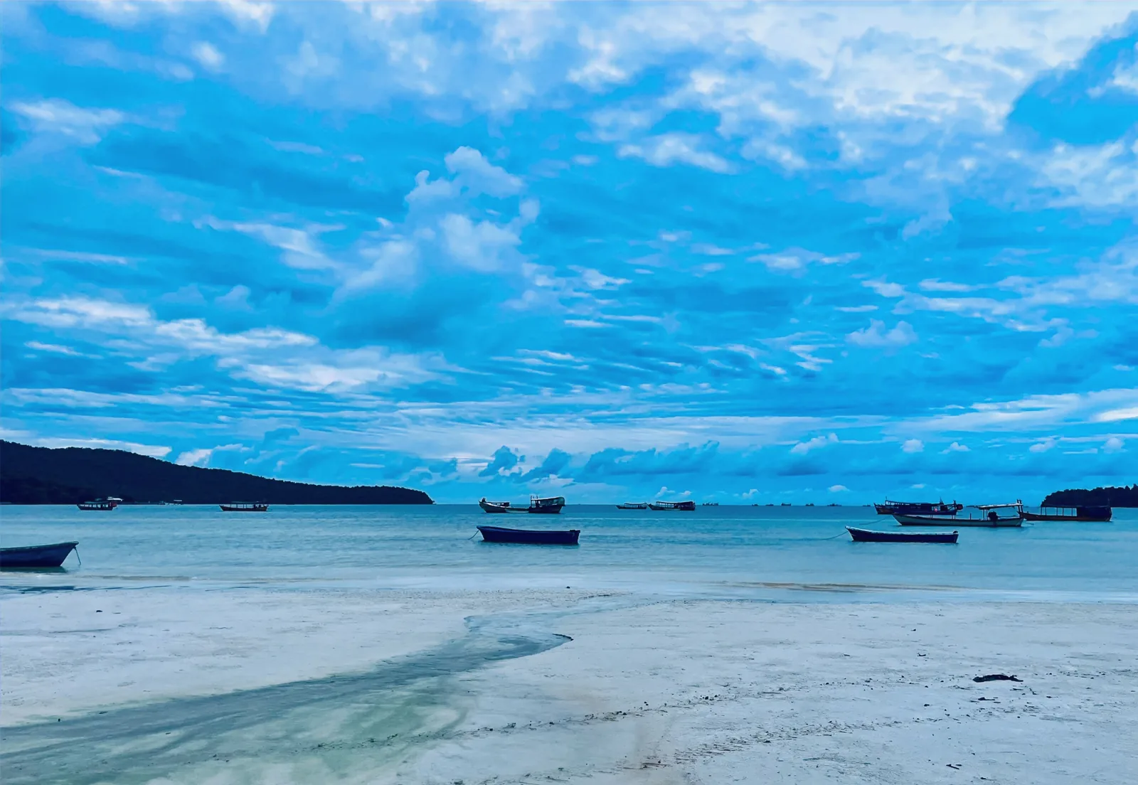 Boats on the beach at sunset with a blue background