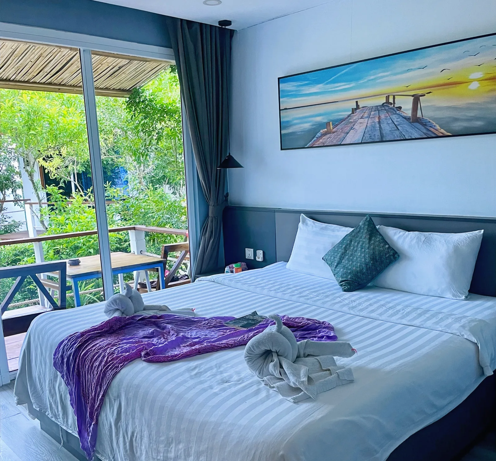 A bed with a sunset painting and a patio
