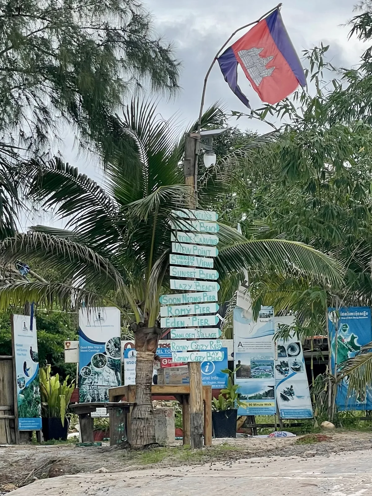 A torn flag of Cambodia on a light post with white and blue signs