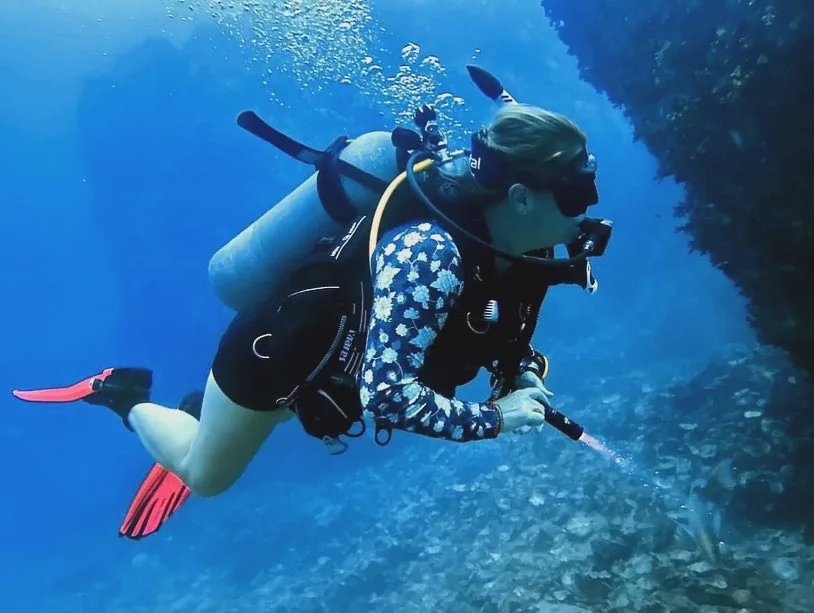 A woman scuba diving underwater with a torch