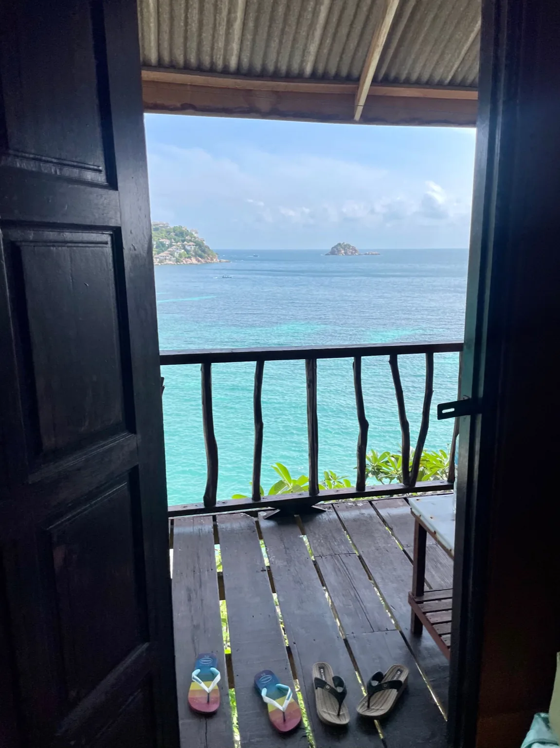 A pair of flip flops on the porch of a wooden hut overlooking the ocean in Koh Tao