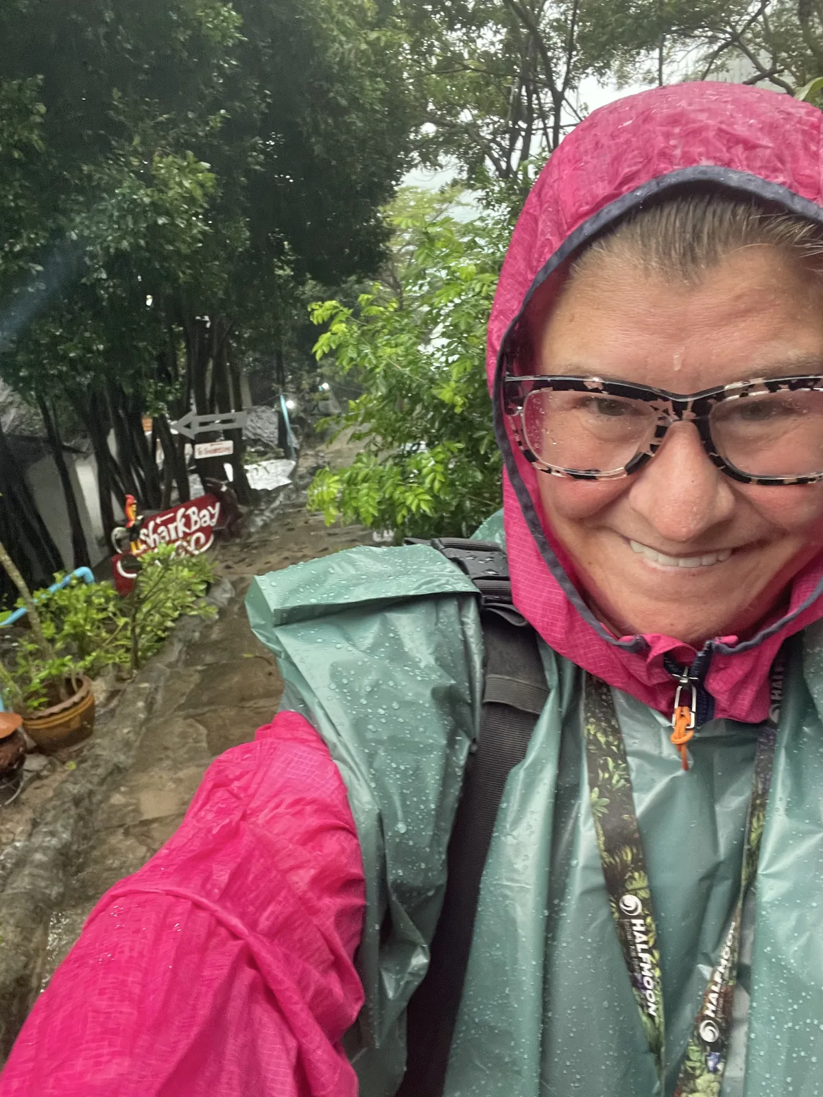 A woman with glasses wearing a pink and green raincoat during the monsoon season in Koh Tao, Thailand