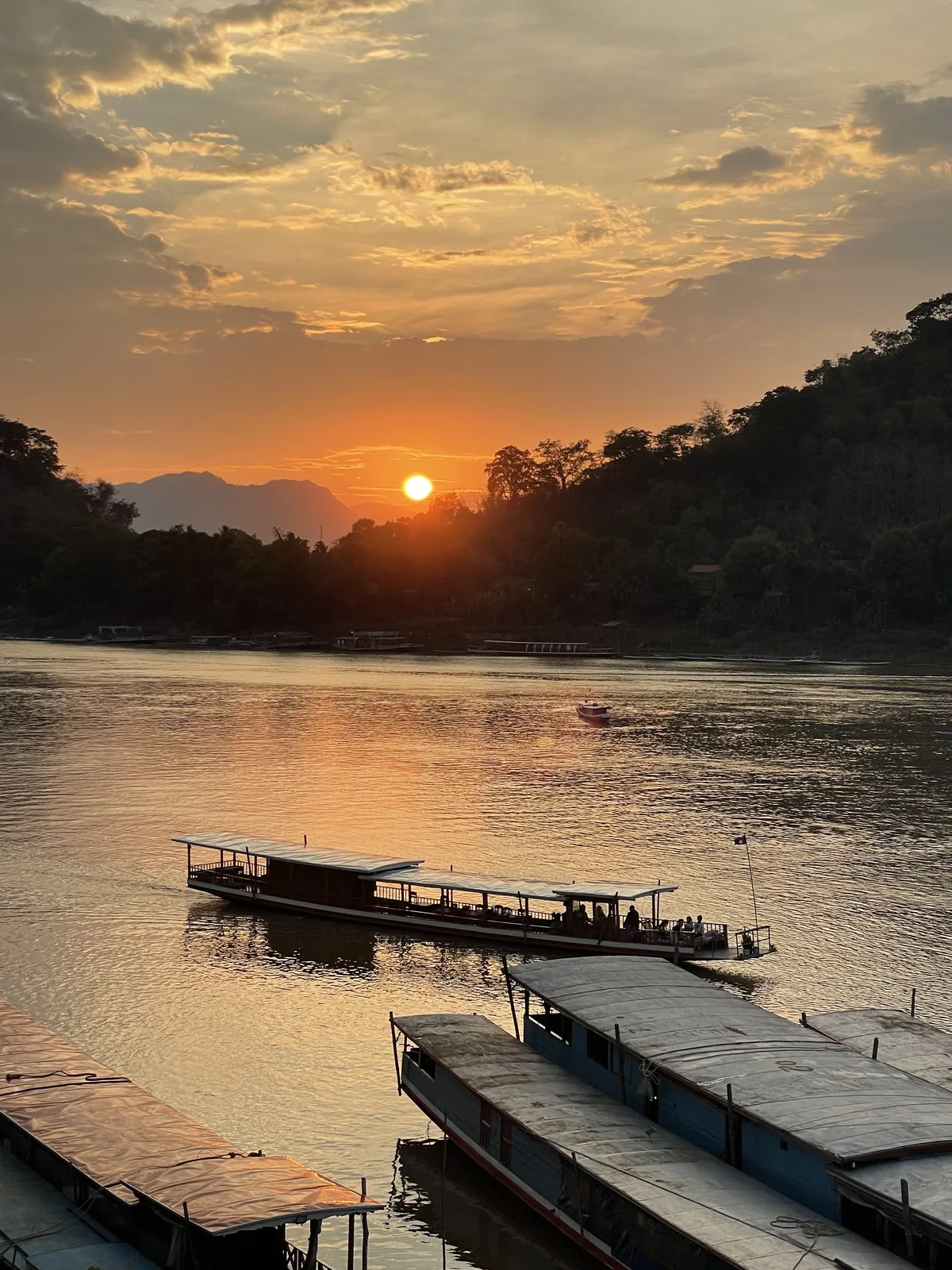 Sunset over the Mekong River with longboats moored at Luang Prabang Laos