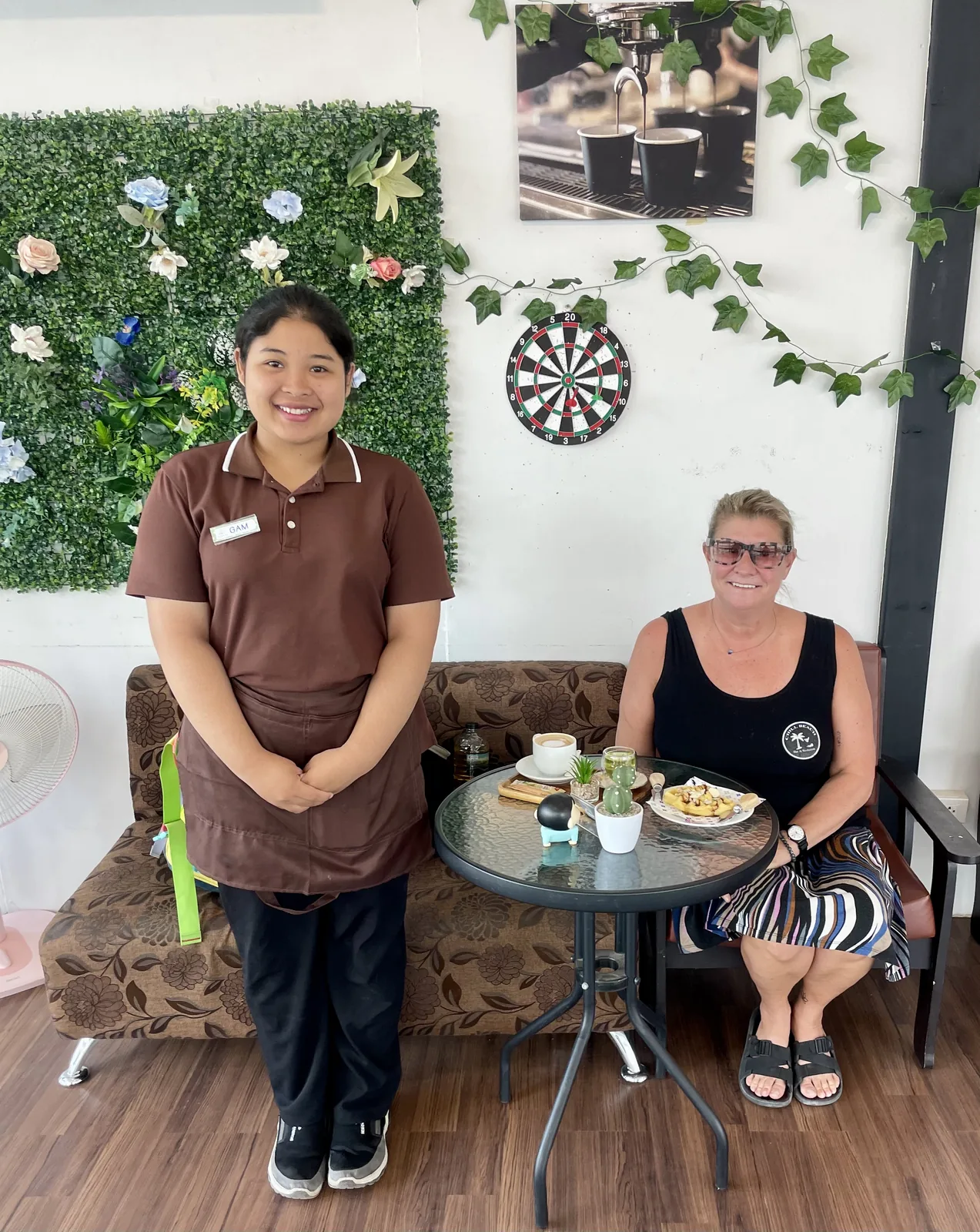 A young barista and an older woman in a coffee shop in Thailand smiling