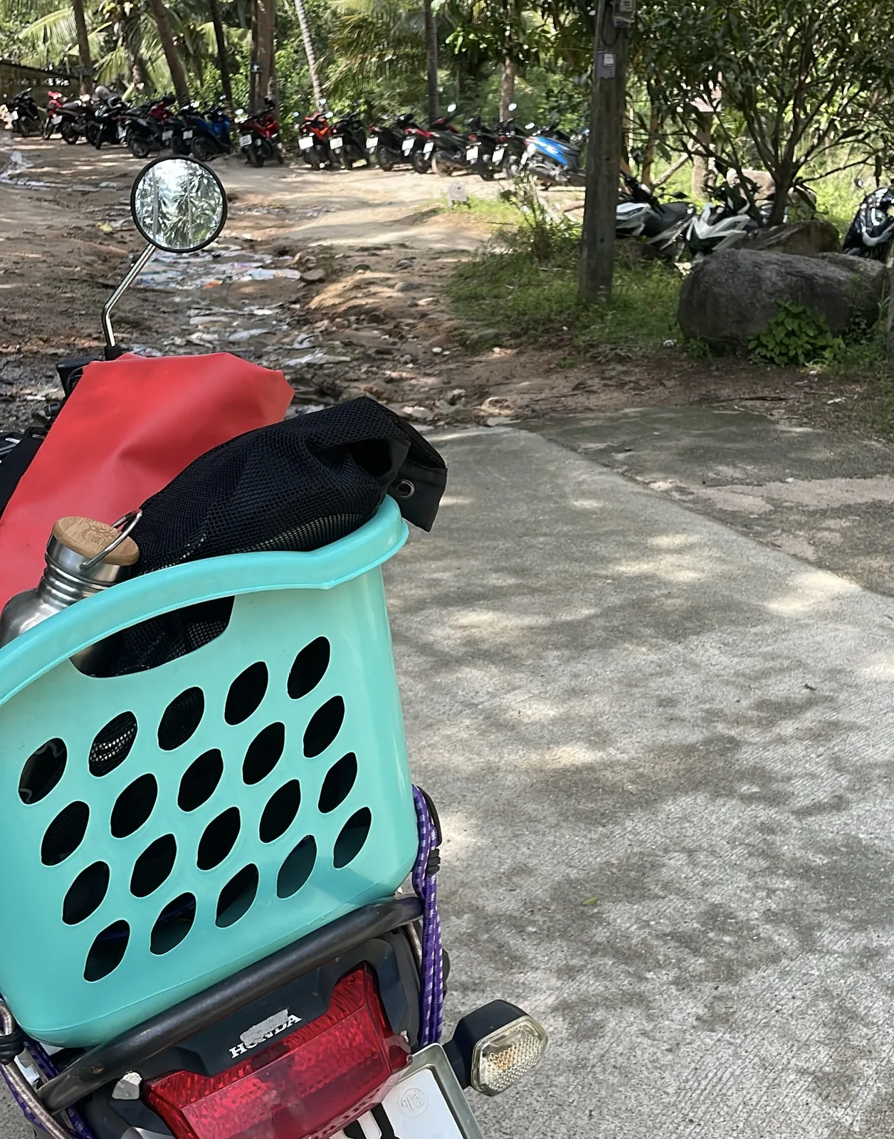 A motorbike with a laundry basket on the back among other motorbikes in Koh Tao