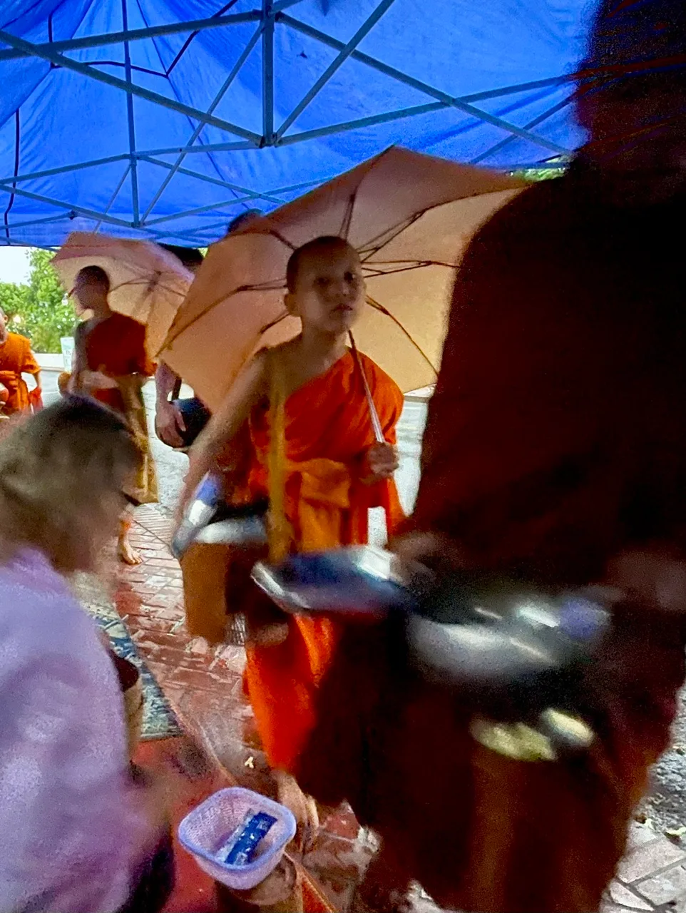 A woman and a young monk with an umbrella during a Buddhist ceremony procession
